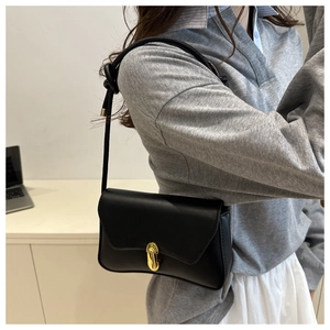 Détail du sac bandoulière noir mat avec boucle dorée et bandoulière à nœud décoratif