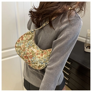 Detailed texture of floral jacquard hobo bag with gold metal plaque on shoulder