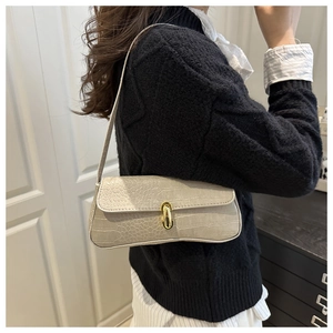 Detail of beige crocodile embossed faux leather shoulder bag with golden U-shaped buckle