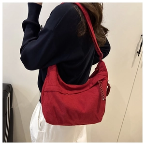 Close-up of red corduroy hobo bag texture with woven zipper detail and spacious design