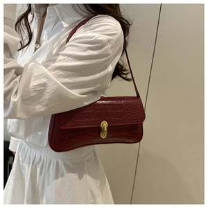 Vue latérale du sac baguette rouge foncé à motif crocodile avec boucle dorée à l'épaule