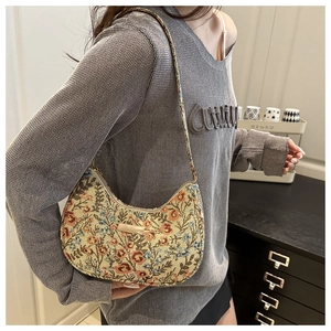 Detailed view of semi-circular jacquard floral underarm bag with metallic logo plaque