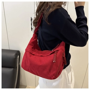 Detail of red corduroy hobo bag with textured stripes and woven zipper pull on model