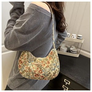Detailed close-up of a floral linen shoulder bag worn by a model in a cozy setting