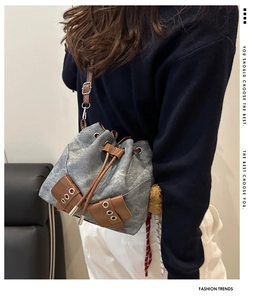 Detailed macro view of washed denim bucket bag with brown leather drawstring and straps
