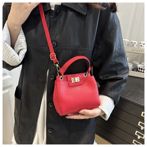 Detail of red lychee pattern leather handbag with gold metal twist lock and handle