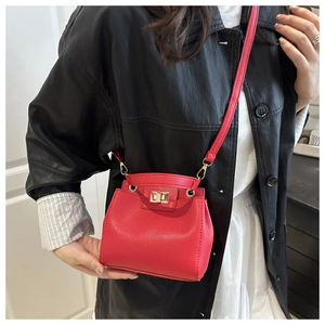 Detail of red lychee pattern leather handbag with gold metal lock and shoulder strap