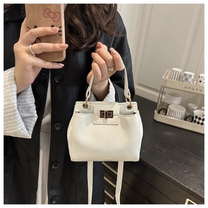 Detailed view of white lychee leather mini bag with gold twist lock and ring handle