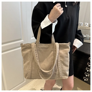 Detail of a large corduroy tote bag featuring dual handles and soft ribbed texture
