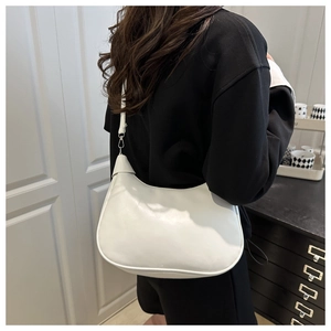 Detailed view of a white minimalist hobo bag worn as a shoulder bag on a female model