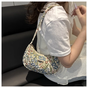 Detail of floral jacquard hobo bag with silver logo plate on lightweight linen fabric