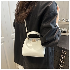 Chic off-white bucket bag with lychee texture and gold twist lock worn by a model