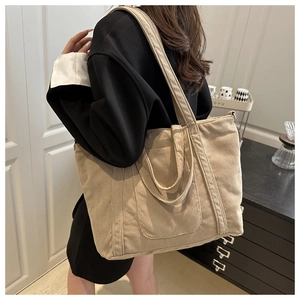 Detail of khaki corduroy tote bag showing ribbed texture and dual straps on model