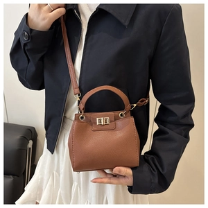 Détail du sac marron avec motif litchi, fermoir doré rotatif et poignée élégante