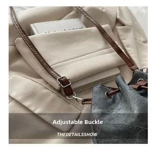 Detail view of denim bucket bag showing adjustable metal buckle and leather shoulder strap