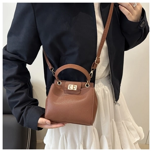 Close-up of brown lychee grain leather bucket bag with metal twist lock on model