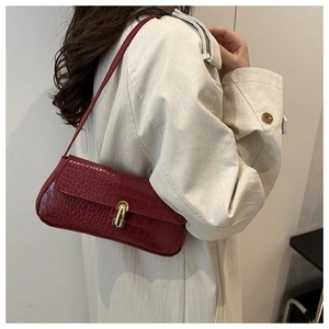 Detail of red crocodile texture underarm bag with gold lock and sleek fashion finish