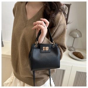 Close-up of black lychee grain leather handbag with elegant gold metal twist lock