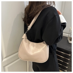 Detail of cream white half-moon shoulder bag with adjustable strap on a black sweatshirt