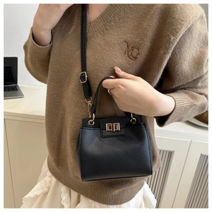 Detail of black lychee grain leather crossbody bag with elegant golden turn-lock closure