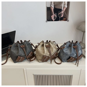 Three vintage canvas bucket bags in grey, khaki, and denim blue with leather drawstrings