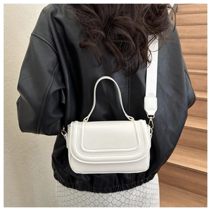 White minimalist crossbody bag with U-shaped stitching on stairs, shown on model