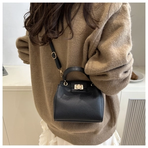 Detail of black pebbled leather bucket bag with gold twist lock and adjustable strap