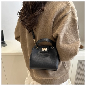 Detail of black lychee texture leather bucket bag with elegant golden square lock