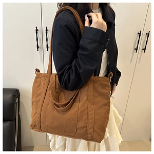Detail shot of brown corduroy tote bag showing soft ribbed texture and long shoulder strap