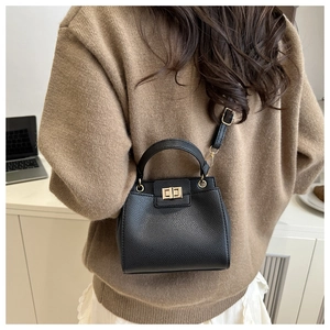 Detailed view of the black lychee pattern leather handbag with gold twist-lock closure
