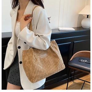 Detail of beige corduroy tote bag showing ribbed texture and fashion label detail