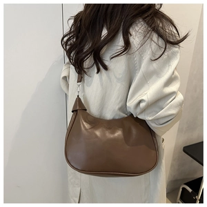 Detailed view of the brown leather texture and silver buckle on the vintage dumpling bag
