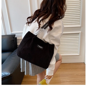 Detail of black corduroy tote bag with metallic chain strap and fashion label on body