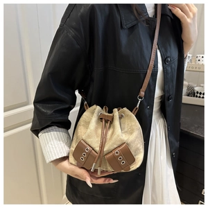 Detail of canvas bucket bag showing brown leather drawstring and metal eyelet accents