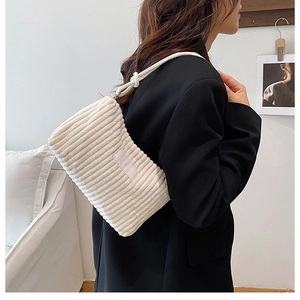 Gros plan d'un sac sous le bras en velours côtelé crème avec texture nervurée et nœud