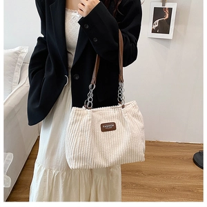 Detail of off-white corduroy texture with chain strap and leather handle on shoulder bag