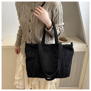 Detail of large black corduroy tote bag showing textured vertical stripes and dual handles
