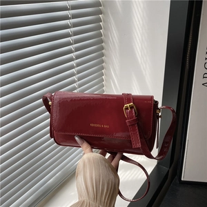 Luxurious burgundy patent leather handbag with gold buckle and adjustable strap