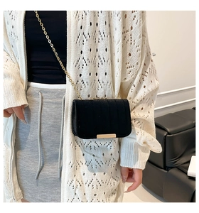 Detailed view of black velvet crossbody bag with gold chain and vertical quilted texture