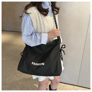 Detail of black tote bag with white FASHION print and striped rope shoulder strap