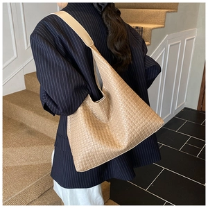 Close-up of beige woven texture and wide shoulder strap on a large leather tote bag