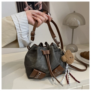 Detail view of charcoal bucket bag with drawstring closure and brown leather straps
