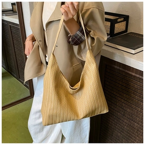 Detailed close-up of woven hobo tote bag in beige with dense herringbone pattern texture