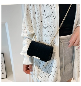 Detail of a chic quilted crossbody bag with gold chain strap shown on a model