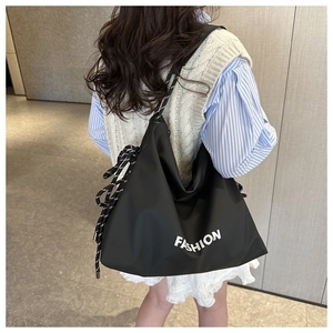Detail of a large black nylon tote bag with a nautical rope strap and fashion print