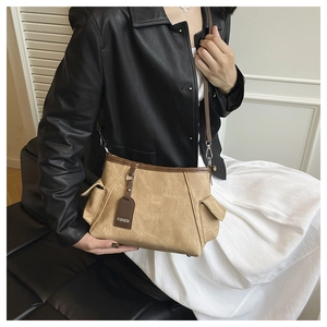 Détail du sac cabas en toile kaki avec garniture en cuir brun et pendentif mode