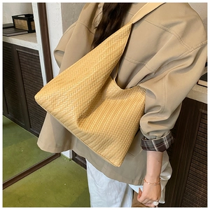 Detail of hand-woven straw tote bag showing khaki textured hobo style shoulder strap