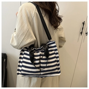 Detail of blue and white striped canvas tote bag with front pockets and black strap