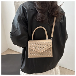 Detail of beige crossbody bag with silver rivet studs on PU leather and top handle