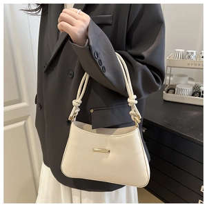 Détail d'un sac sous le bras blanc cassé minimaliste avec bandoulière nouée et doré